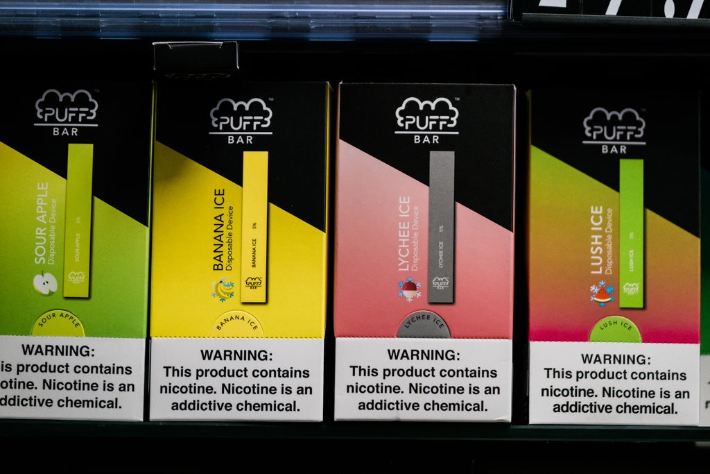 Four Puff Bar products in a retail display each is a different flavor: sour apple, banana ice, lychee ice, lush ice